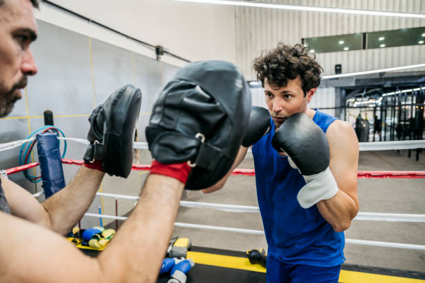 istock Men working out with focus mitts in boxing ring 1271030960