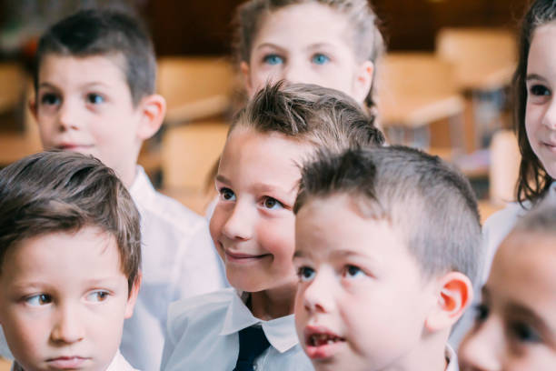 istock Schoolmates standing in the classroom, looking at thier teacher 1271031132