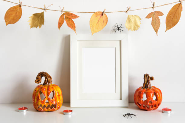 istock Halloween ceramic pumpkins, floral garland and frame on table wall background. Greeting card template 1271031190