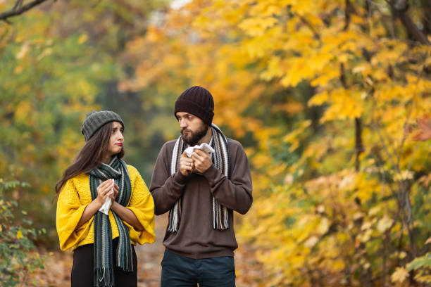 homem doente e menina espirrar e assoar o nariz no outono no parque - autumn women leaf scarf - fotografias e filmes do acervo