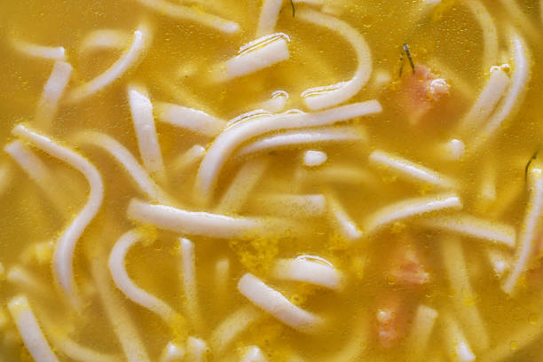 An abstract image of tasty chicken soup with noodles and dill weed.