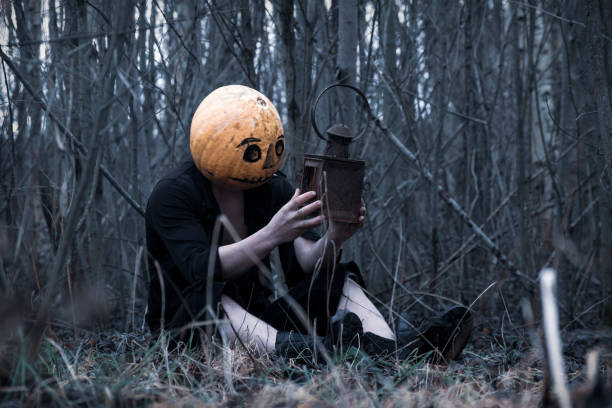 Lost in the woods a guy in a pumpkin with a lantern with a candle wanders in search of a means of getting rid of the autumn depression