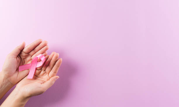 ヘルスケアと乳がんの意識の概念。ピンクのリボンを持つ手、乳がんの意識、女性の乳房腫瘍に対する意識を高める象徴的な弓の色。 - world in hands ストックフォトと画像