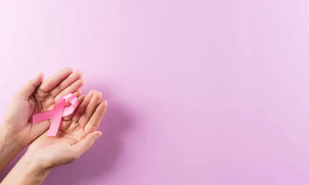 Photo of Healthcare and breast cancer awareness concept. Hands holding pink ribbons, Breast cancer awareness, symbolic bow color raising awareness on women's breast tumor.