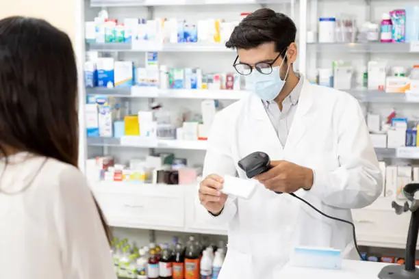 Photo of Middle eastern male pharmacist scanning barcode