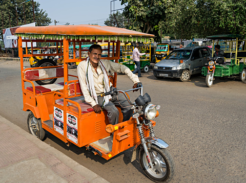Stock photo showing the backs of a passenger and an auto rickshaw driver as seen by a passenger on a journey in the back seat.