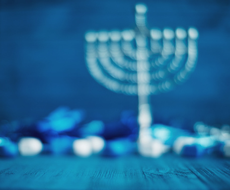Jewish holiday Hanukkah concept with menorah, traditional donuts and gift box on wooden table.