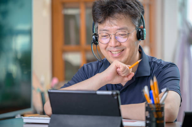 Middle-aged Asian man working at home. Telecommuting concept. stock photo