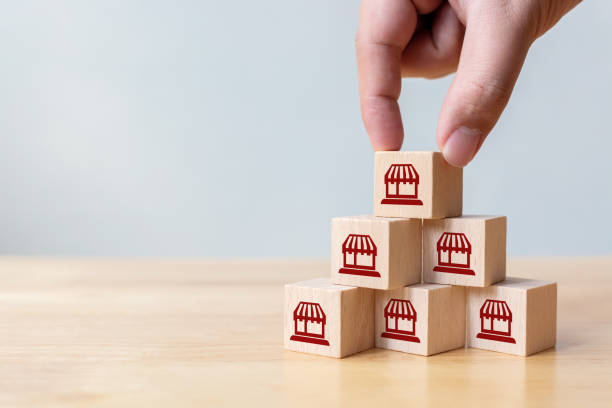 Franchise business marketing system concept. Structure service store network strategy. Hand putting wooden block on top with icon store