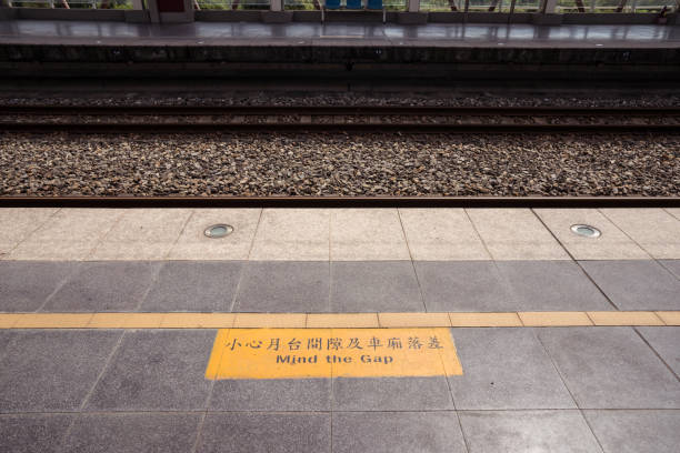 знак на полу, говоря mind gap в цяньцзя железнодорожной станции - timeboard стоковые фото и изображения