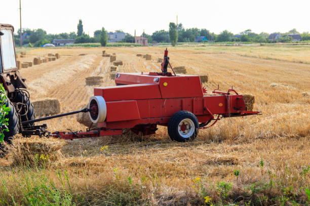 Rectangular baler discharges a straw bale in a field during the harvesting process Rectangular baler discharges a straw bale in a field during the harvesting process hay baler stock pictures, royalty-free photos & images