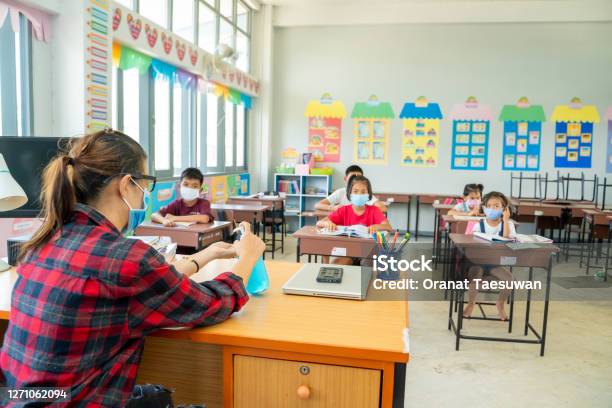 Group Of School Kids With Teacher Sitting In Classroom Online And Raising Handselementary School Stock Photo - Download Image Now