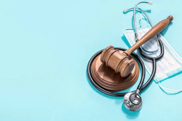 Photo of Wooden judge gavel with medical mask and stethoscope on blue background Healthcare legislation and medical concept