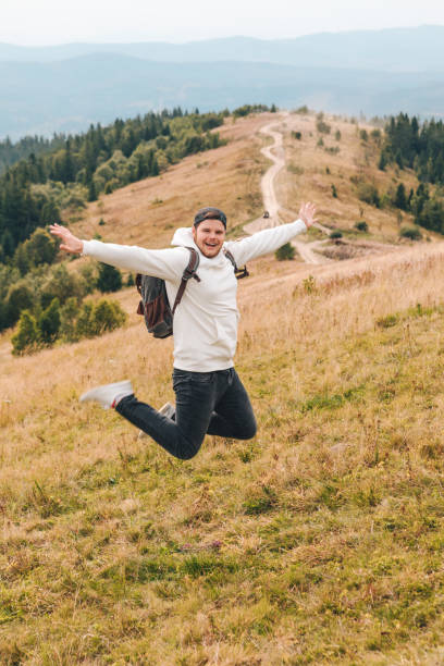 istock man with backpack happy jumping on the peak on the mount 1271070527