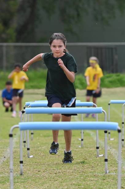 молодая девушка работает препятствие - hurdle sports track track and field playing field стоковые фото и изображения
