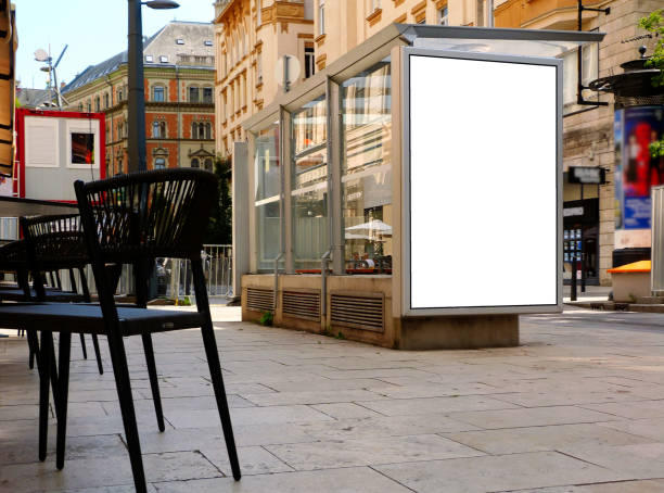 bus shelter on urban downtown street. white poster and ad display and light box bus shelter and bus stop along urban street. glass and aluminum structure. city street with trees. blank area for poster and ad display. light box. banner and copy space. selective focus. mock-up base bus shelter stock pictures, royalty-free photos & images