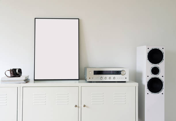 istock Poster Frame Mockup in white modern interior. Modern audio stereo system with white speakers on bureau in modern interior. 1271078283