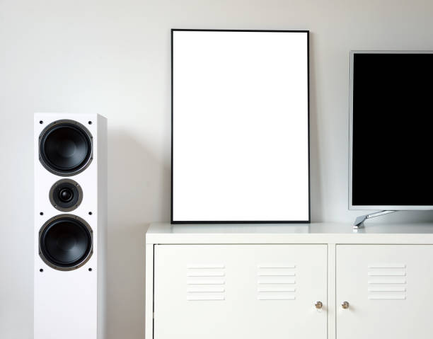 istock Poster Frame Mockup in white modern interior. Modern audio stereo system with white speakers on bureau in modern interior. 1271078317