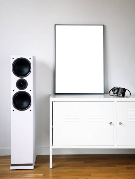 istock Poster Frame Mockup in white modern interior. Modern audio stereo system with white speakers on bureau in modern interior. 1271078395
