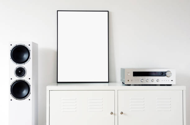 istock Poster Frame Mockup in white modern interior. Modern audio stereo system with white speakers on bureau in modern interior. 1271078442