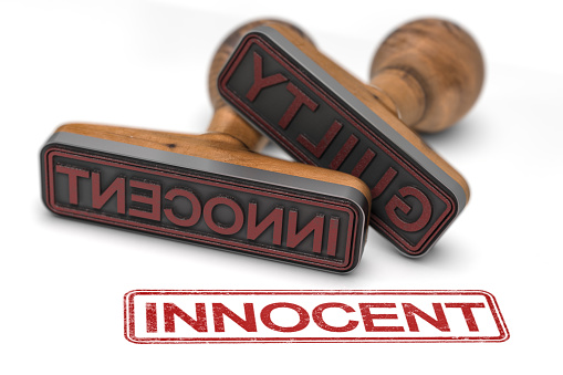 Two rubber stamps over white background with the words guilty and innocent, focus on the second one. 3D illustration