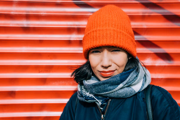 Portrait of woman standing against graffiti. Smiling female is wearing knit hat. She is in warm clothing.
