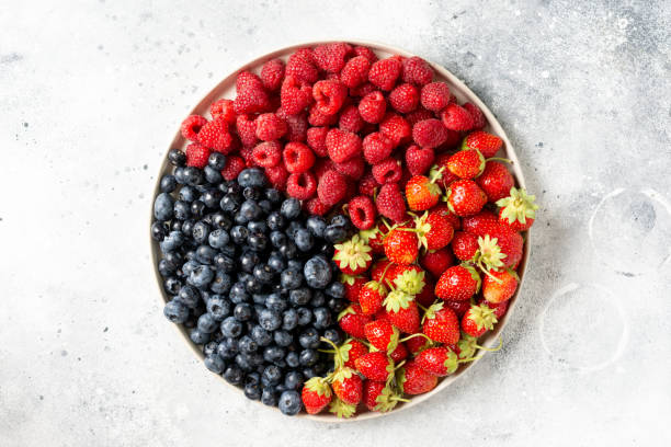 istock Fresh berries. Different berries in a white ceramic plate on a light table. Strawberries, raspberries and blueberries on a plate. Top view with space for text 1271081855