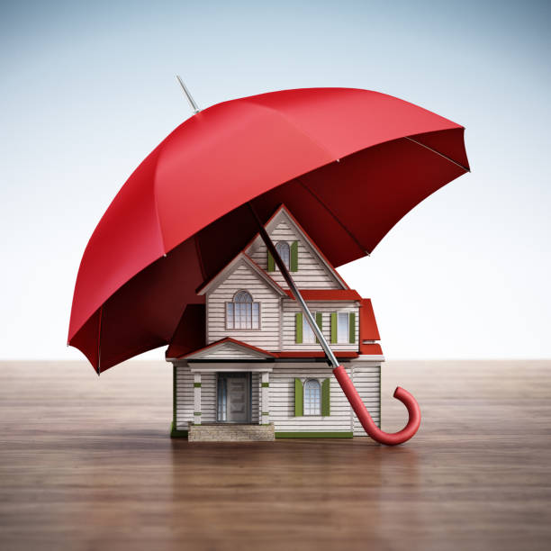 Red umbrella is protecting a toy house on white background. Horizontal composition with selective focus and copy space. Insurance and real estate concept.