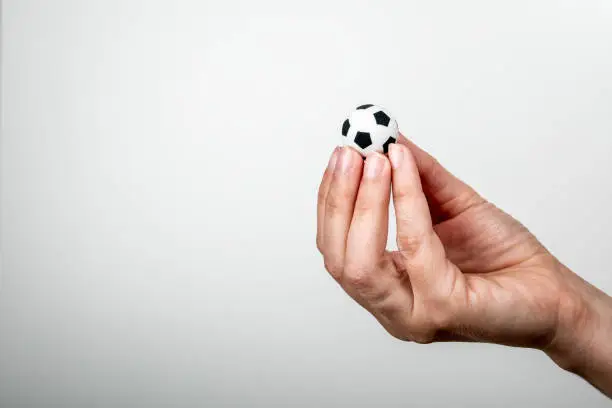 Photo of Miniature soccer ball in woman's hands. Popular sport, entertainment, business and lifestyle concept