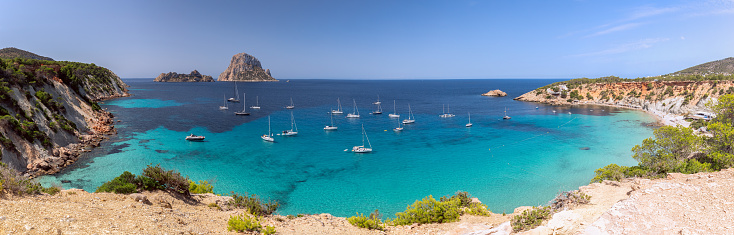 Beautiful Panorama of bay Cala Hort with sea sailing yachts and the mountain Es Vedra. Ibiza, Balearic Islands, Spain