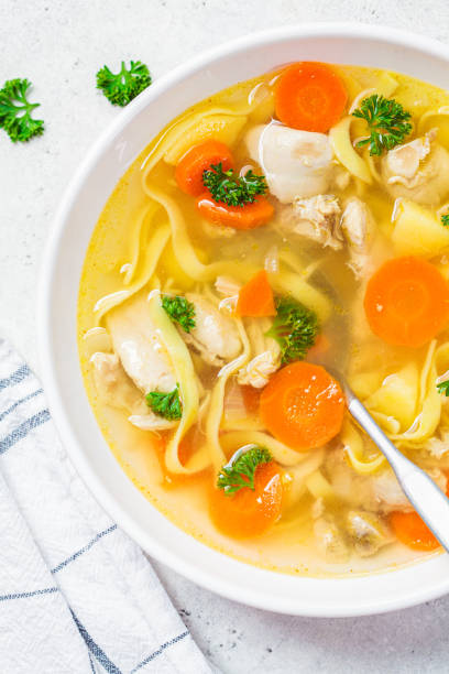 sopa de pollo casera con fideos y verduras en tazón blanco, fondo blanco, vista superior. - noodles pasta chicken breast color image fotografías e imágenes de stock