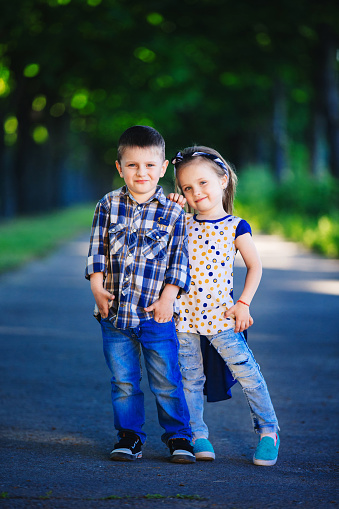 Children's love, a little boy and a girl, having fun, laugh and smile, and kiss outdoors.