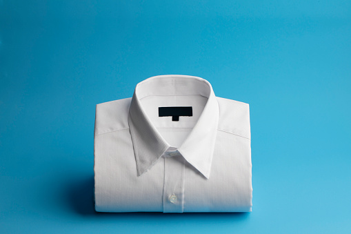 Folded white shirt on blue background