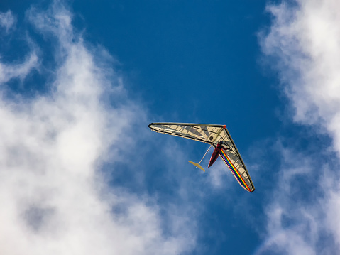 Colorful kite flying in a blue sky with white clouds