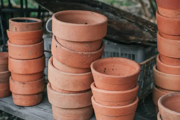 Stacks of vintage old clay flower pots on a rustic wooden surface and background