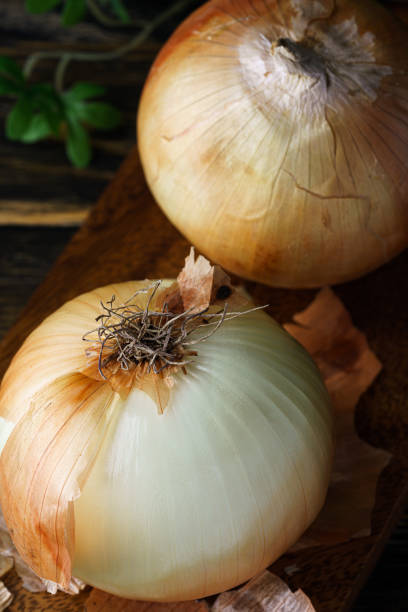 istock Raw unpeeled onions on wooden table 1271096594