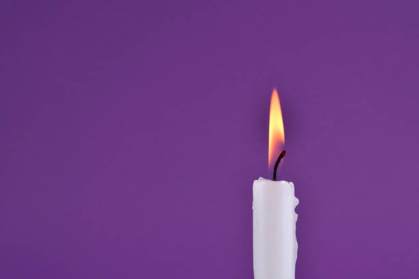 istock Candle with flame burning isolated on purple background 1271097198