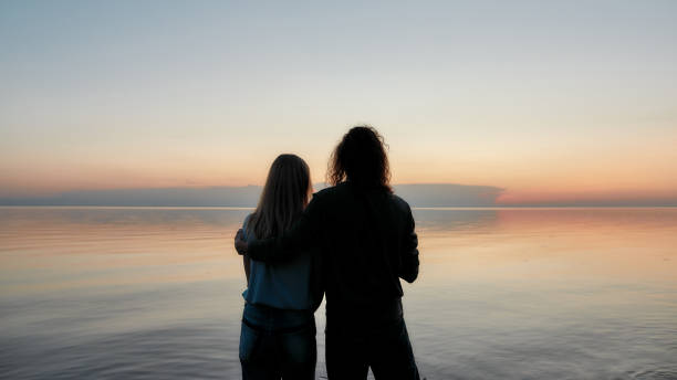 istock Silhouetted couple embracing while watching beautiful sunset on the river together 1271097629