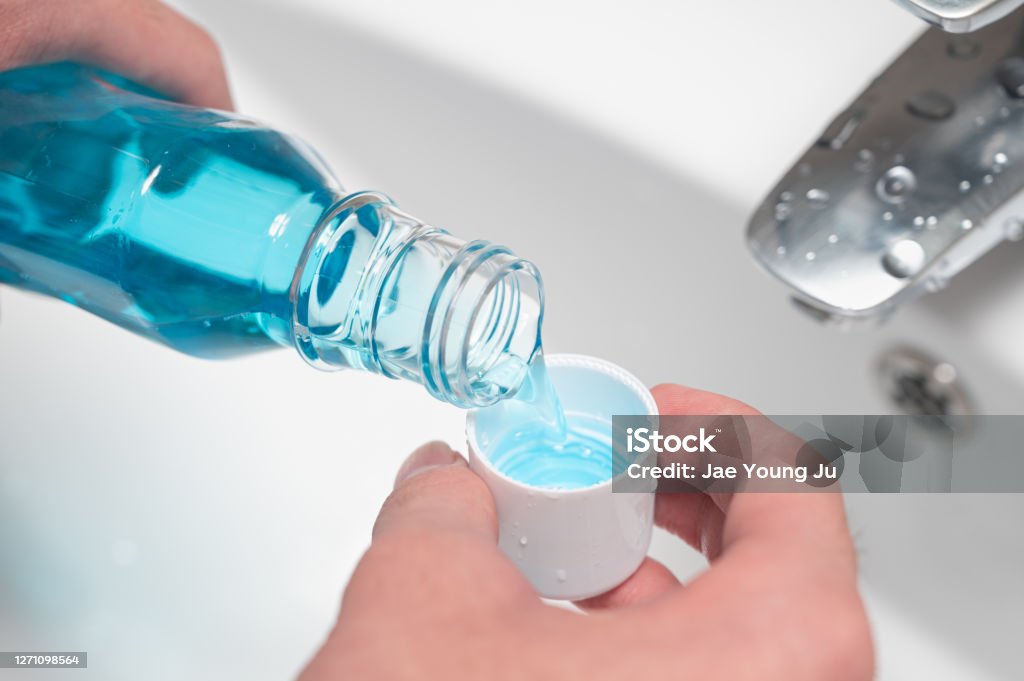 Hand of man Pouring Bottle Of Mouthwash Into Cap. Mouthwash Stock Photo