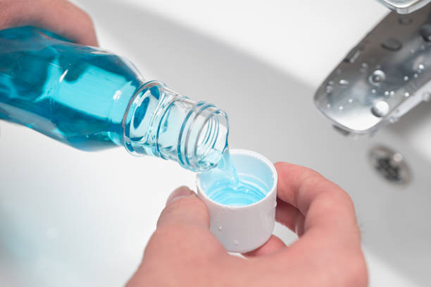 Hand of man Pouring Bottle Of Mouthwash Into Cap. stock photo