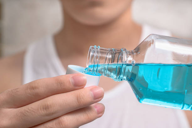 hand of man pouring bottle of mouthwash into cap. - going into imagens e fotografias de stock