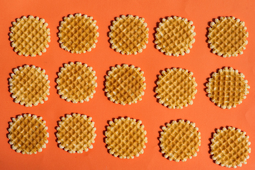 Sweet Waffles pastel texture pattern on orange background flat lay top view. Food backgrounds abstract