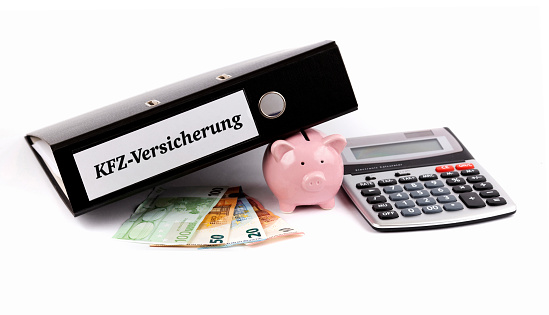 Folder with German car insurance documents, piggy bank and euro banknotes on a white background
KFZ-Versicherung