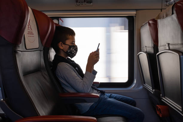 istock Young boy sitting in seat using a smart phone on train journey. 1271100787