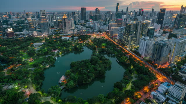 Time lapse of Bangkok cityscape and Lumpini park green space view, day to night