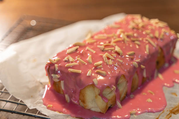 raisin pound cake recipe topped with almond in strawberry syrup placed on wooden table - cheesecake syrup almond cream imagens e fotografias de stock