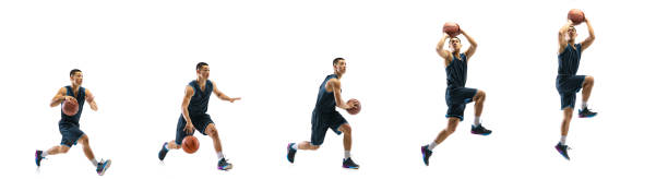 Young basketball player against white studio background in motion of step-to-step goal Higher. Young basketball player of team training in action, motion in jump of step-to-step goal isolated on white background. Concept of sport, movement, energy and dynamic, healthy lifestyle. taking a shot sport photos stock pictures, royalty-free photos & images