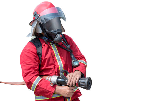 Portrait of a firefighter in protective uniform holding a firefighting and fire hose nozzle. The individual stands confidently against a white background
