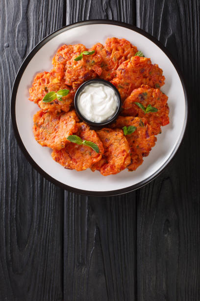 Domatokeftedes tomato fritters are a famous and delicious delicious Santorini dish made with ripe tomatoes, onions and feta cheese close-up in a plate. Vertical top view Domatokeftedes tomato fritters are a famous and delicious delicious Santorini dish made with ripe tomatoes, onions and feta cheese close-up in a plate on the table. Vertical top view from above domato stock pictures, royalty-free photos & images