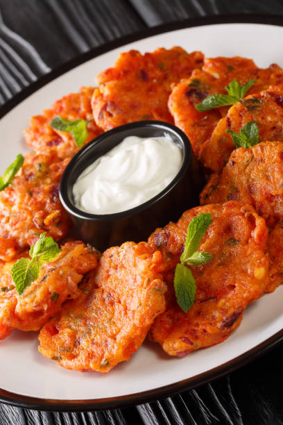 Domatokeftedes Recipe Greek tomato fritters served with yogurt close-up in a plate. Vertical Domatokeftedes Recipe Greek tomato fritters served with yogurt close-up in a plate on the table. Vertical domato stock pictures, royalty-free photos & images